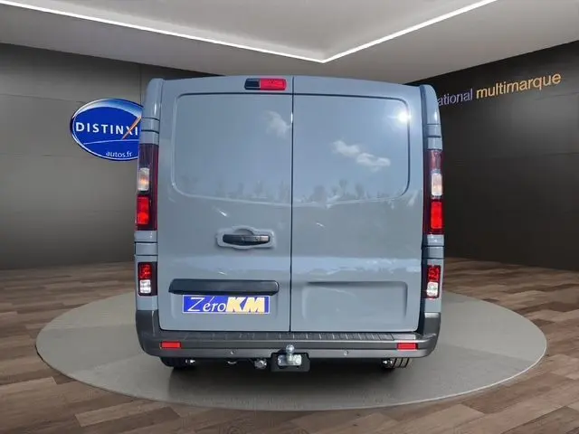 Vue arrière du Renault Trafic Cabine Approfondie gris urbain avec attelage et portes battantes fermées dans un showroom.