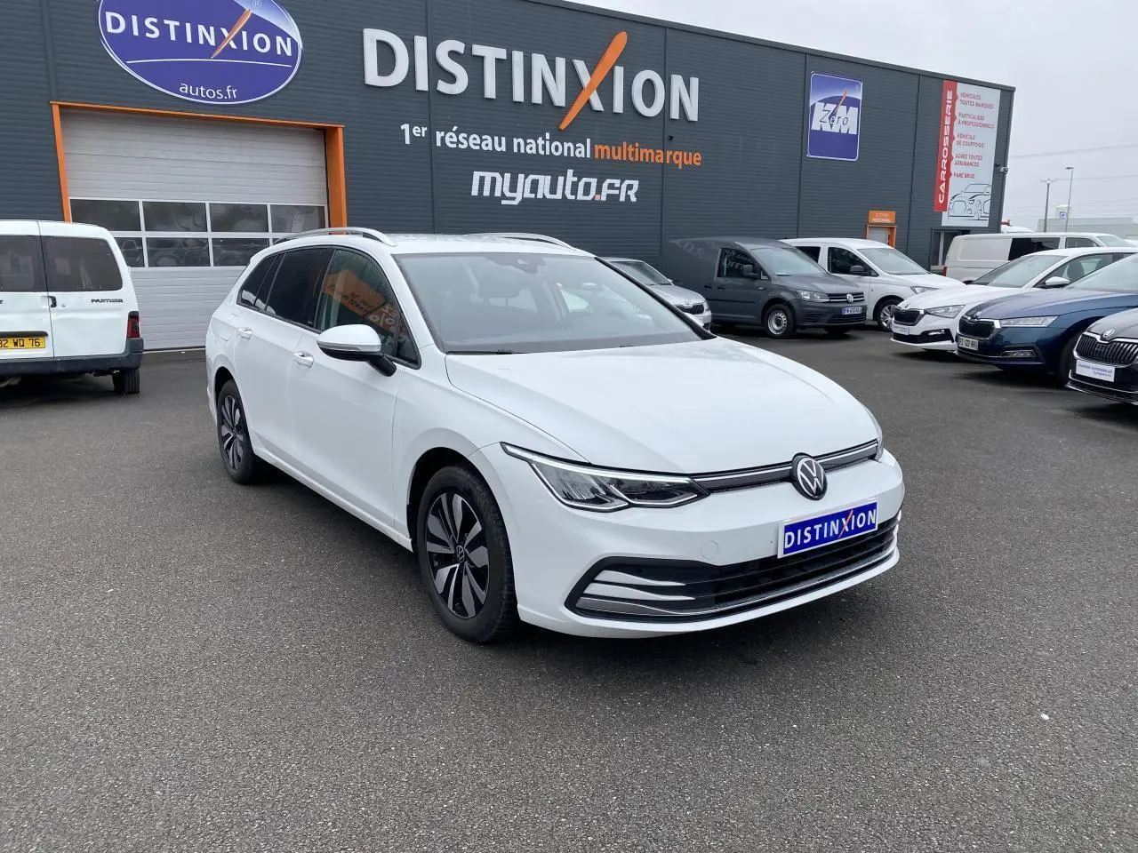 Volkswagen Golf SW blanc oryx vue 3/4 avant droit, avec vitres arrière surteintées et jantes spécifiques.