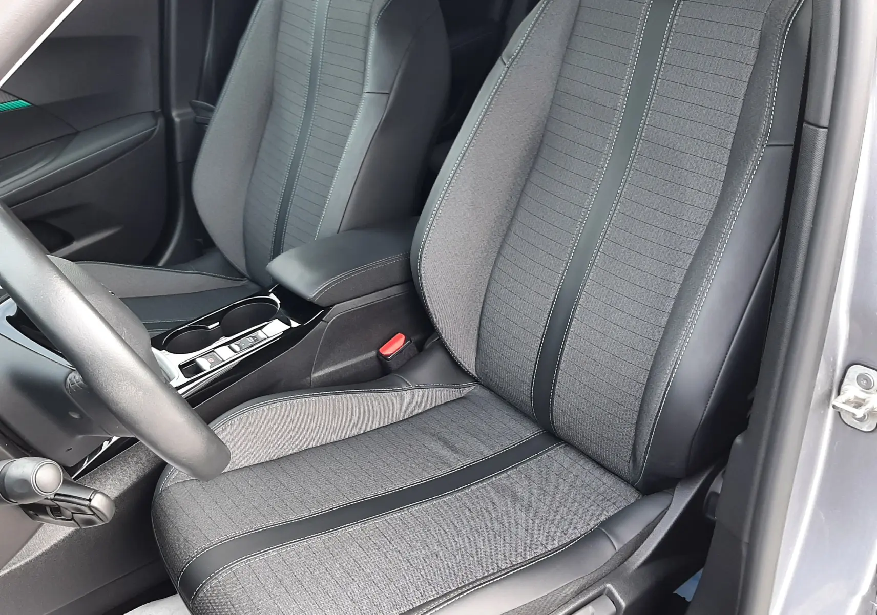 Intérieur du Peugeot 2008 gris 2021, vue rapprochée des sièges avant en tissu gris et cuir noir avec coutures contrastées.