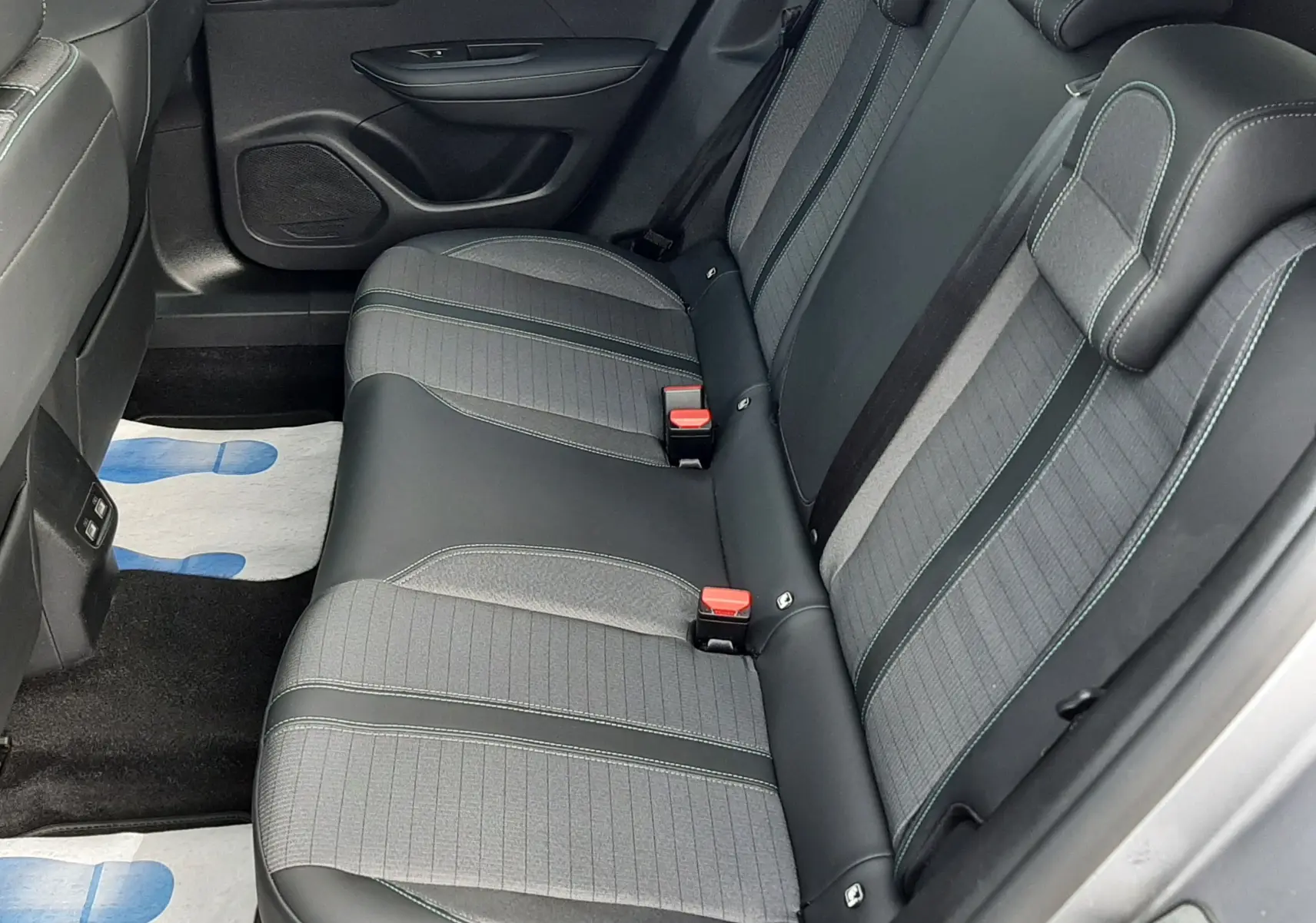 Vue latérale droite de l'intérieur arrière du Peugeot 2008 gris 2021, sièges en tissu et cuir noir avec surpiqûres vertes.