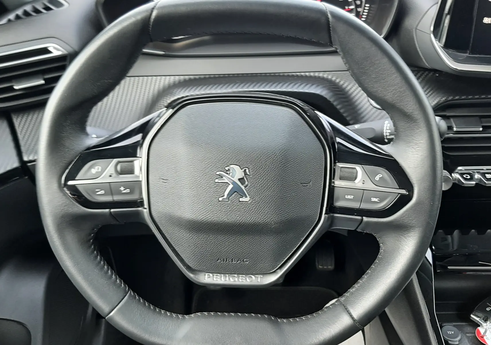 Vue rapprochée du volant cuir noir du Peugeot 2008 gris 1.5 BlueHDi 110 Allure avec commandes intégrées.