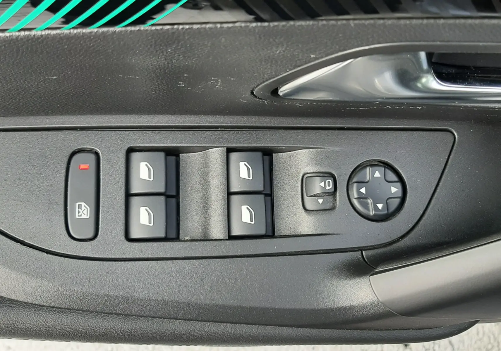 Panneau de commandes des vitres et rétroviseurs côté conducteur du Peugeot 2008 gris, intérieur noir.