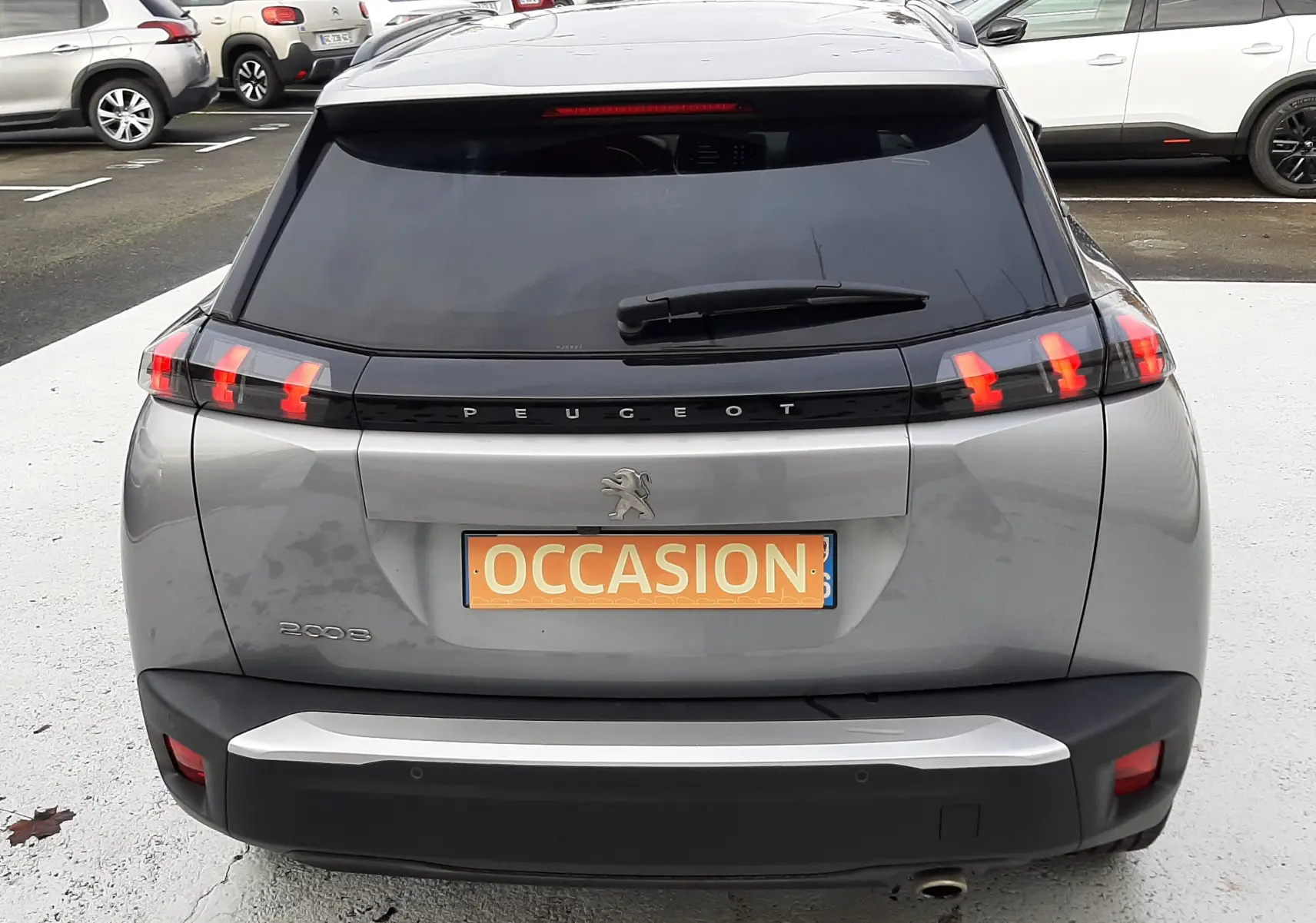Vue arrière d'un Peugeot 2008 gris 2021 avec feux arrière à griffes rouges et lunette arrière teintée.