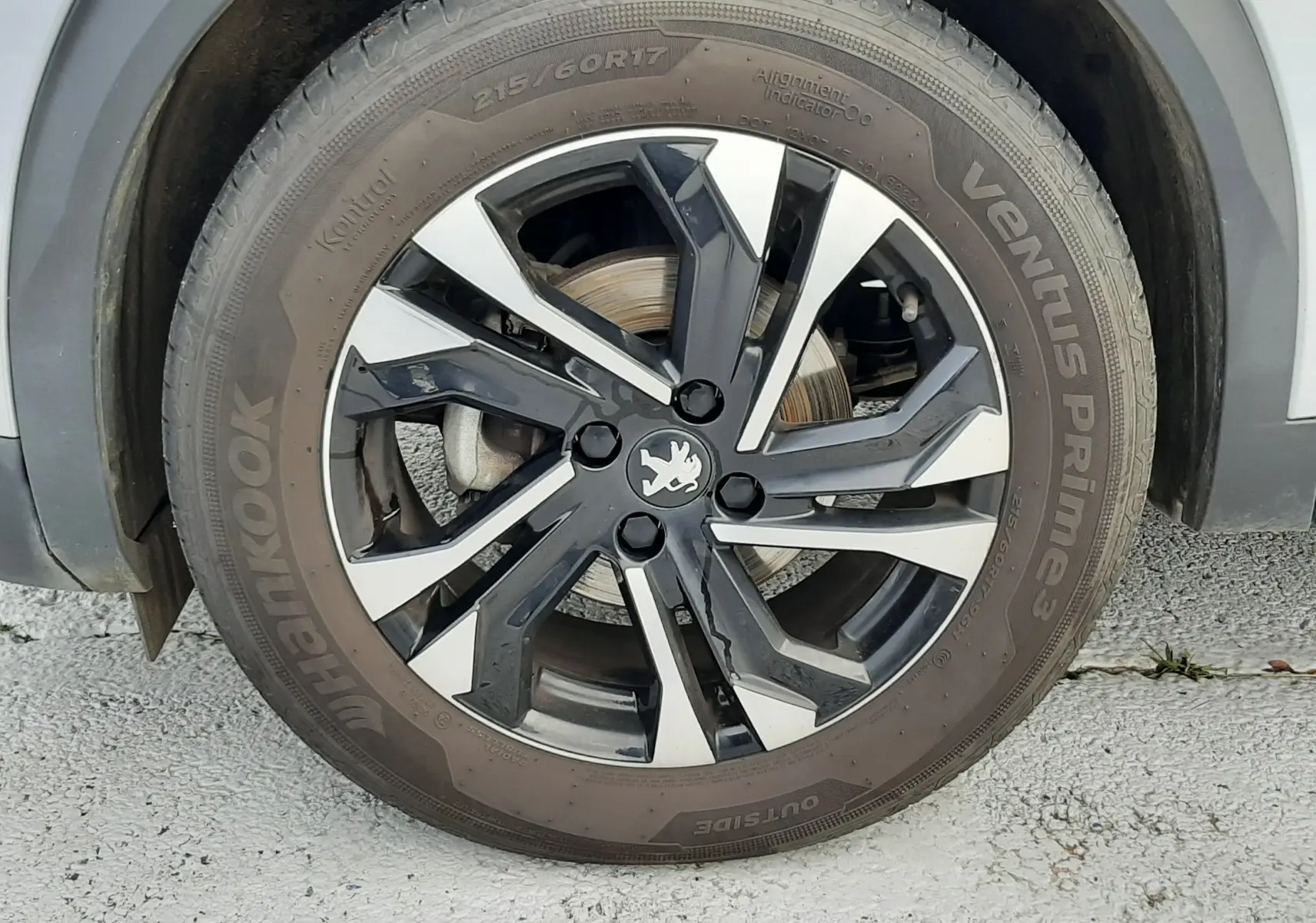 Gros plan sur la roue avant gauche gris clair d'un Peugeot 2008 1.5 BlueHDi 110 Allure avec jante alliage bicolore.