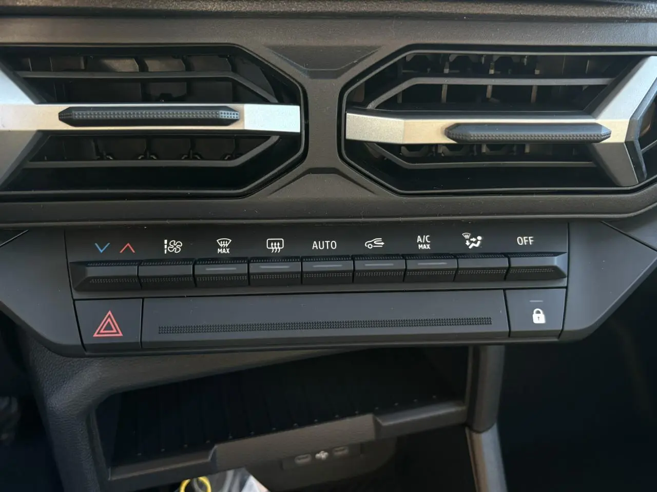 Vue rapprochée de la console centrale du Dacia Duster blanc glacier 2026, montrant les commandes de climatisation et les aérateurs.