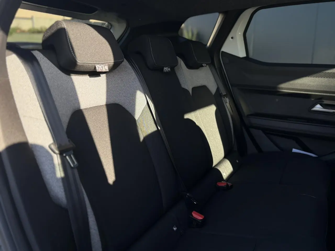Vue latérale intérieure du siège arrière noir et gris du Dacia Duster 2026, avec ceinture de sécurité et appuie-têtes visibles.