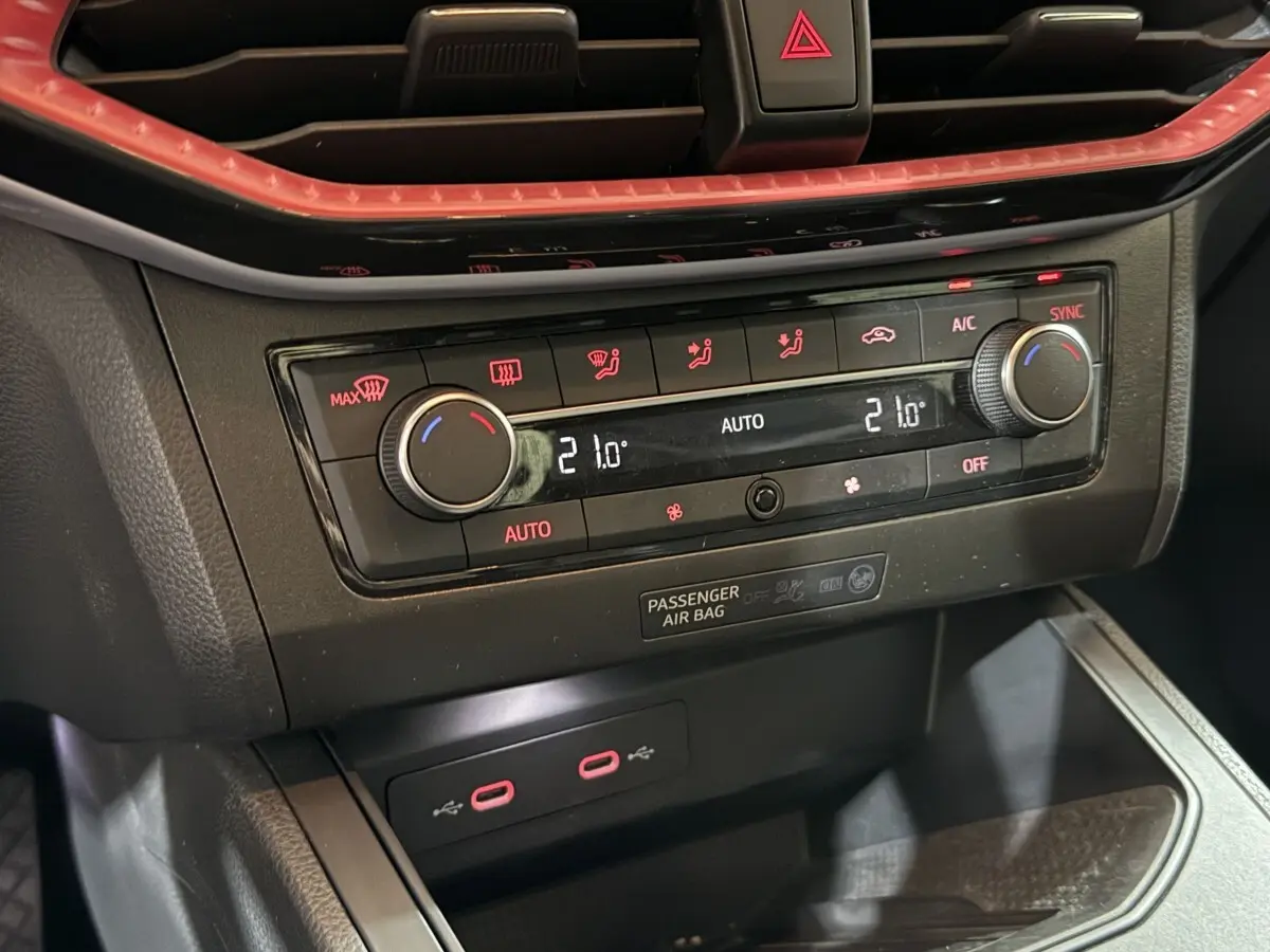 Gros plan sur la commande de climatisation digitale et ports USB rouges du tableau de bord noir de la SEAT Ibiza 2024.