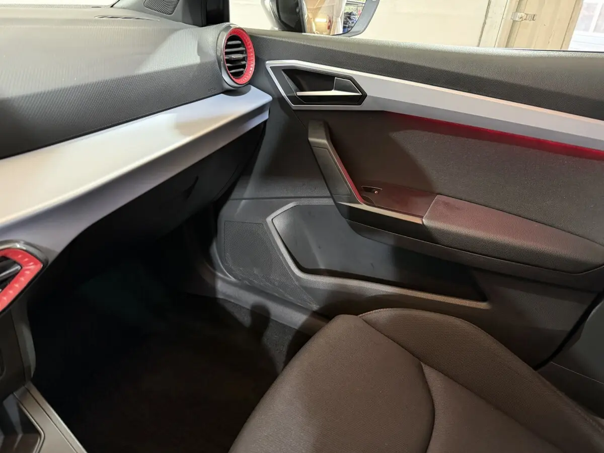 Intérieur côté passager de la SEAT Ibiza 1.0 TSI 110 FR 2024, avec tableau de bord noir et cerclage rouge des aérateurs.