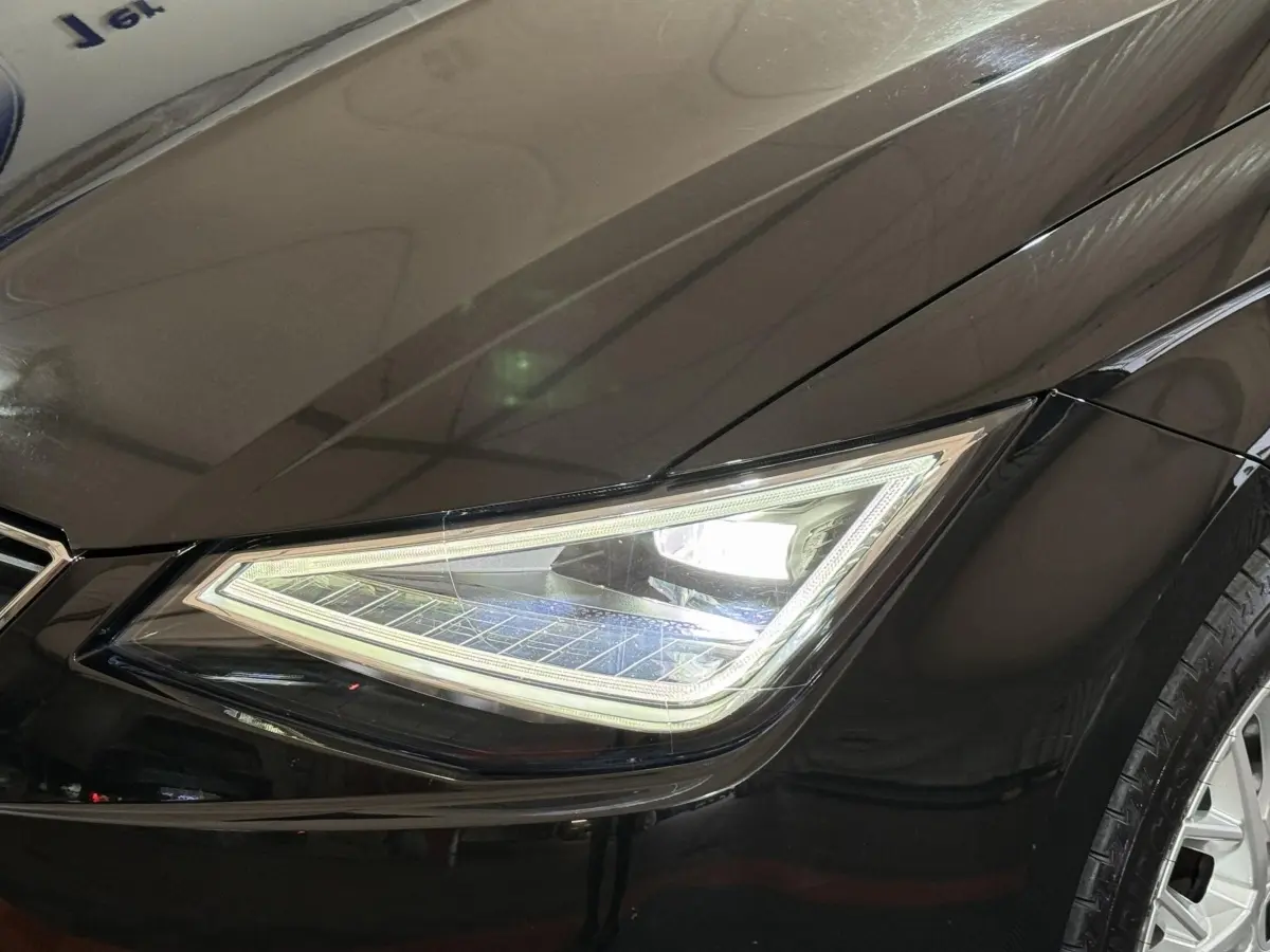 Gros plan sur le phare avant droit allumé d'une SEAT Ibiza 2024 noire, soulignant ses lignes angulaires modernes.