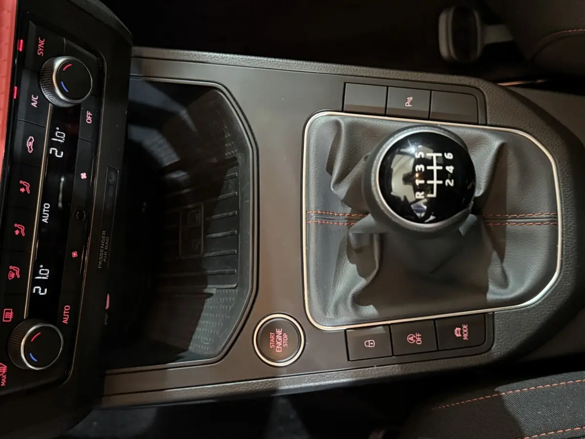 Vue rapprochée de la console centrale noire de la SEAT Ibiza 1.0 TSI 110 FR 2024, avec levier de vitesses manuel et commandes éclairées.