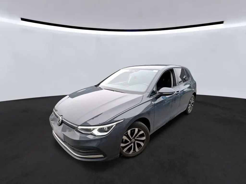 Volkswagen Golf 1.5 eTSI gris vue 3/4 avant droit dans un studio avec phares LED allumés.