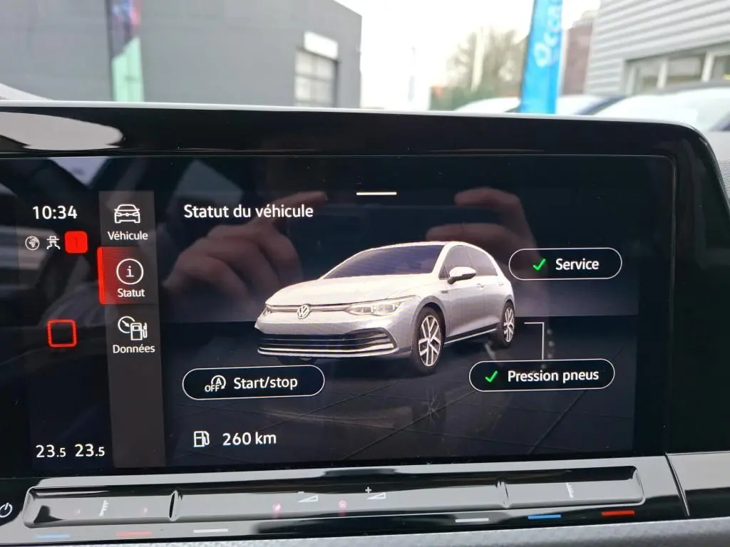 Écran intérieur affichant le statut d’un Volkswagen Golf gris en vue 3/4 avant avec alertes service et pression pneus validées.
