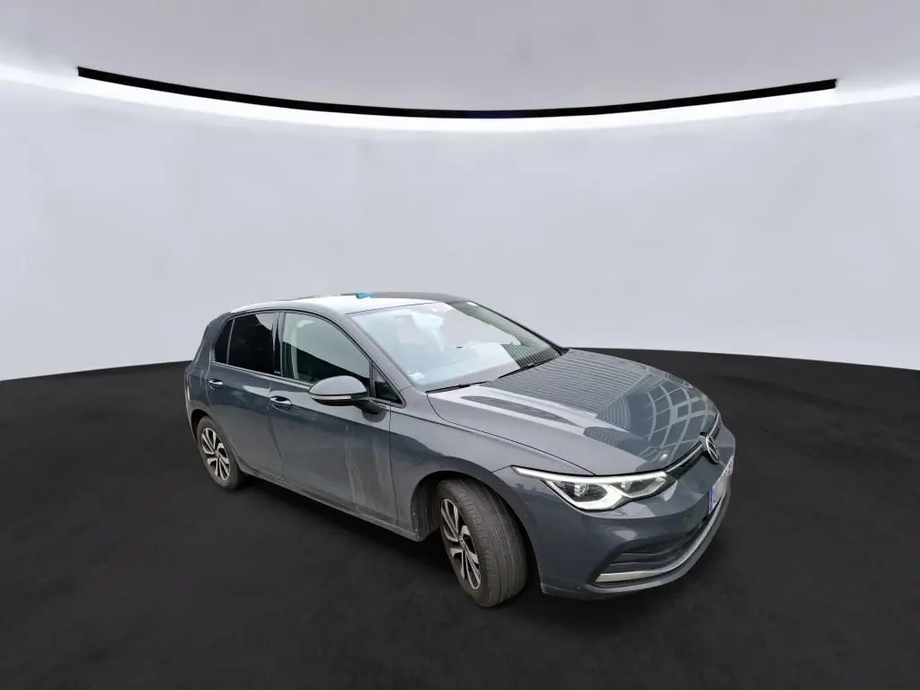 Volkswagen Golf 1.5 eTSI gris vue 3/4 avant droit avec phares LED allumés sur fond neutre.