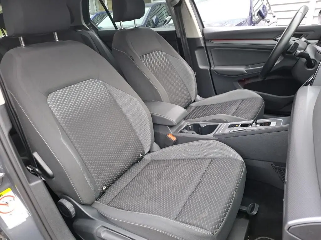 Vue intérieure côté conducteur de la Volkswagen Golf 1.5 eTSI 130 DSG7 Active 2022 avec sièges tissu gris et console centrale.
