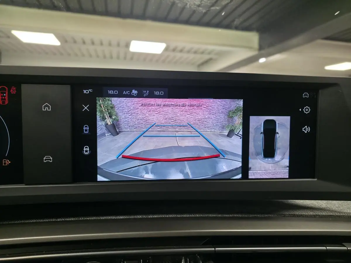 Écran de caméra de recul affichant l'arrière noir brillant du Peugeot 3008 hybride avec lignes de guidage colorées.