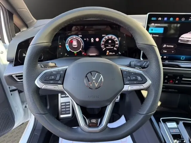 Vue centrée sur le volant cuir multifonctions de la Volkswagen Golf blanche avec tableau de bord numérique et écran tactile.