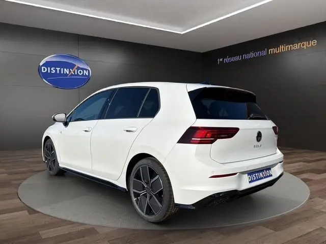 Vue 3/4 arrière droite d'une Volkswagen Golf blanche 2025 R-Line avec toit panoramique et jantes noires distinctives.
