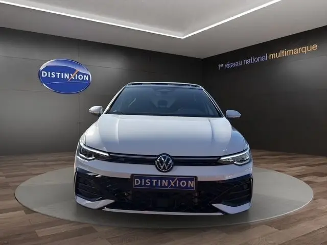 Vue frontale d'une Volkswagen Golf 2.0 TDI blanche avec toit panoramique et calandre R-Line dans un showroom.