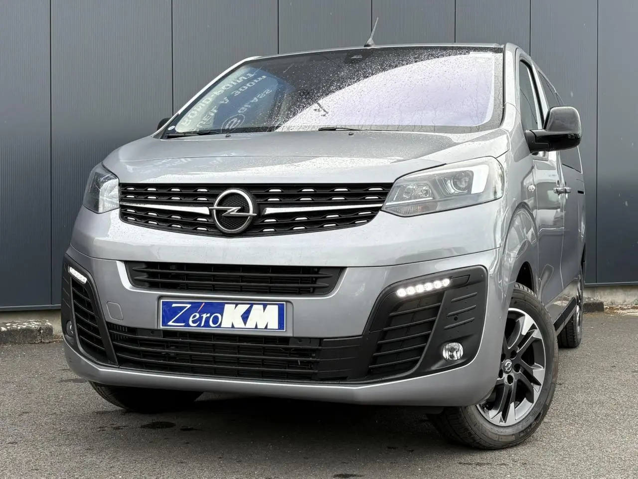 Vue 3/4 avant droit d'un Opel Zafira Life XL gris Artense avec calandre noire et feux LED allumés.