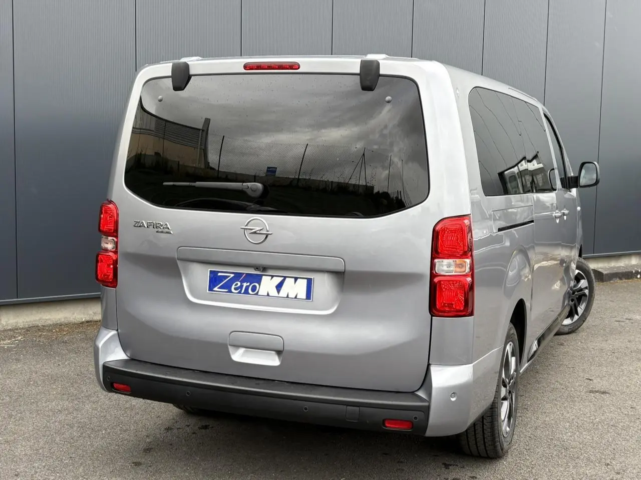 Vue 3/4 arrière droite de l'Opel Zafira Life XL gris Artense avec vitres teintées et feux arrière rouges.