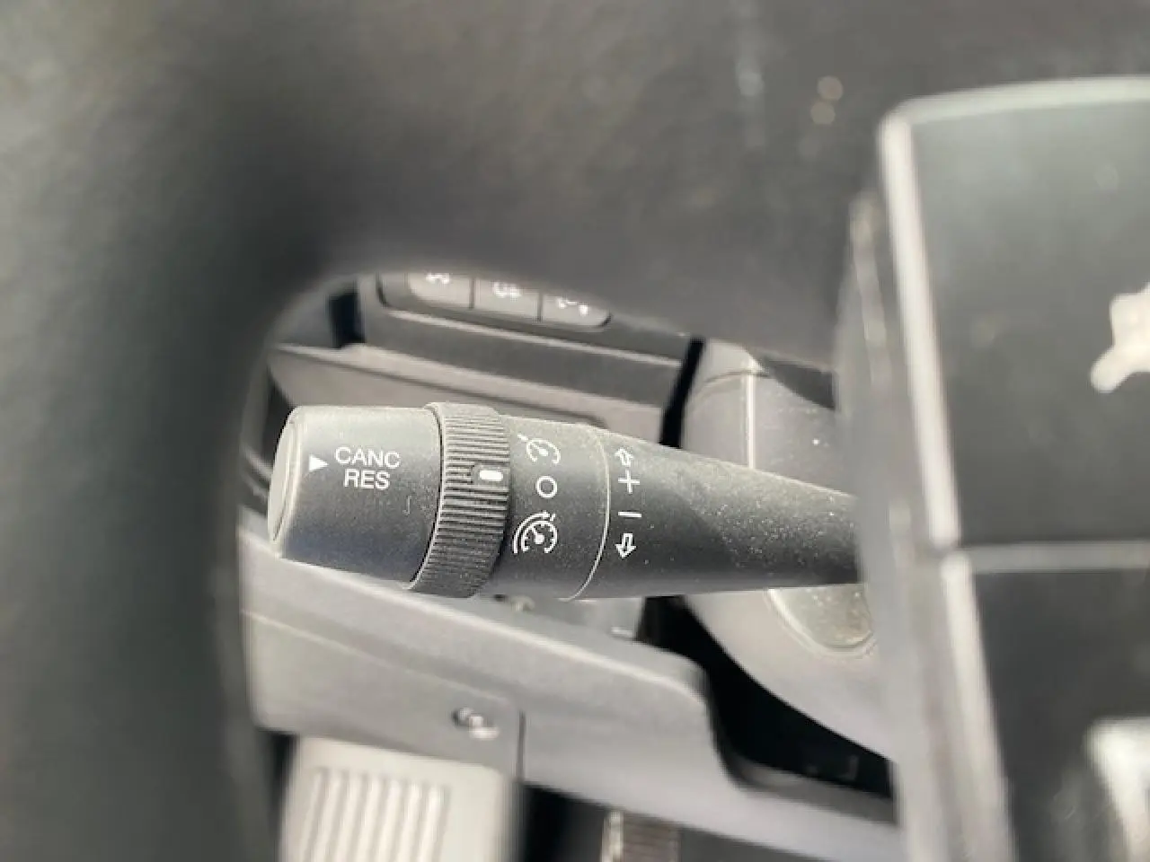 Gros plan sur la commande de régulateur de vitesse à gauche du volant dans l'habitacle du fourgon Opel Movano blanc.