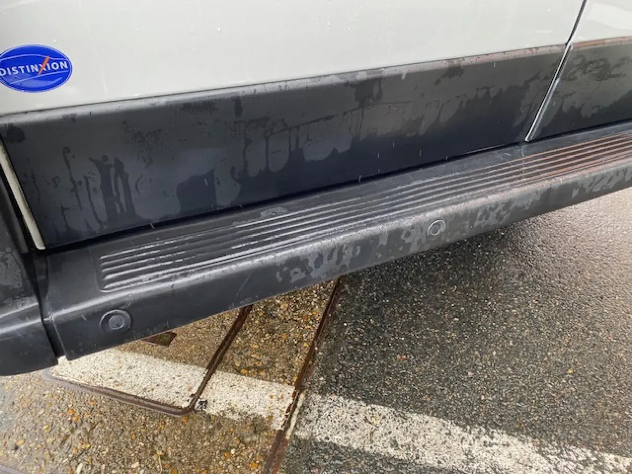 Gros plan sur la bas de caisse noir et la marche-pied d'un Opel Movano Fourgon blanc, côté droit, avec badge Distinxion.