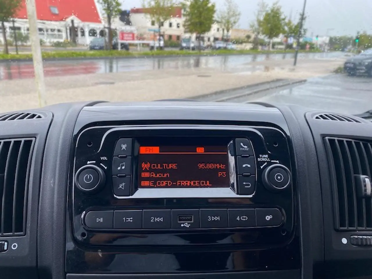 Vue rapprochée du tableau de bord noir de l'Opel Movano Fourgon 2023 avec radio affichant une station FM.