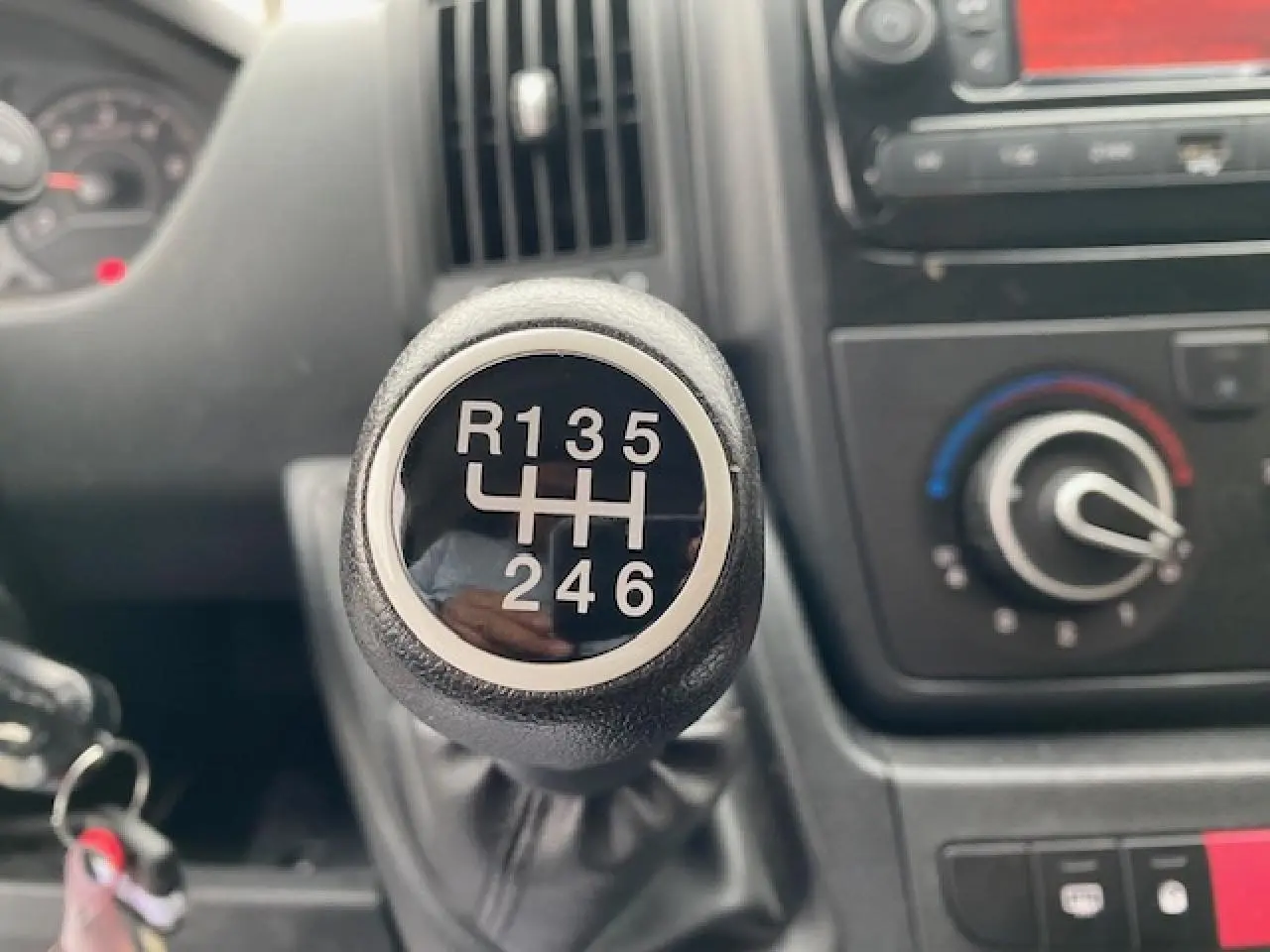 Le levier de vitesses manuel en gros plan de l'Opel Movano Fourgon blanc, avec la console de climatisation en arrière-plan.