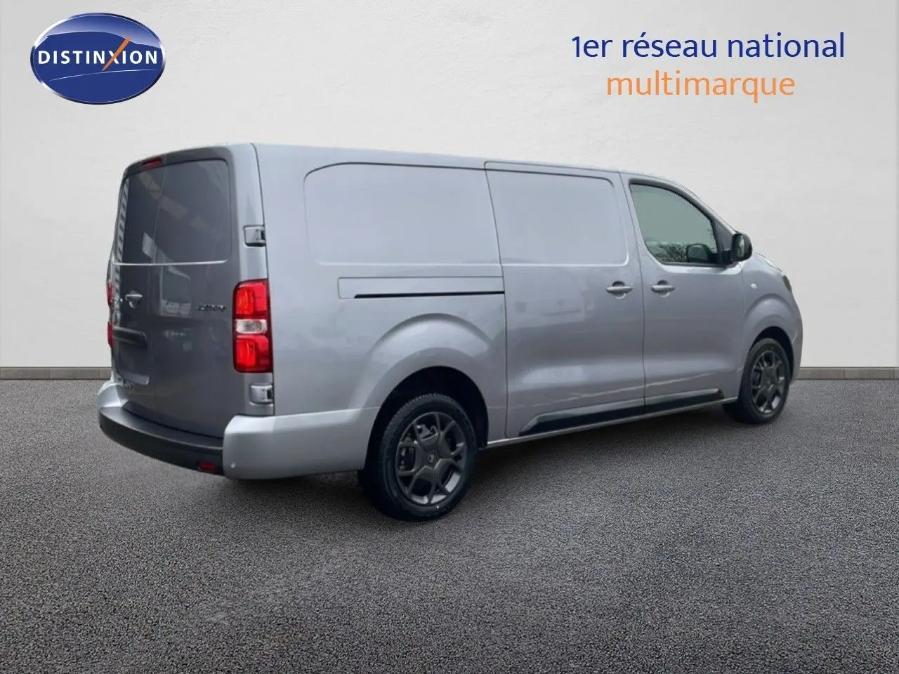 Vue 3/4 arrière droite d’un Citroën Jumpy gris Artense métallisé, fourgon long avec jantes noires et vitres arrière teintées.