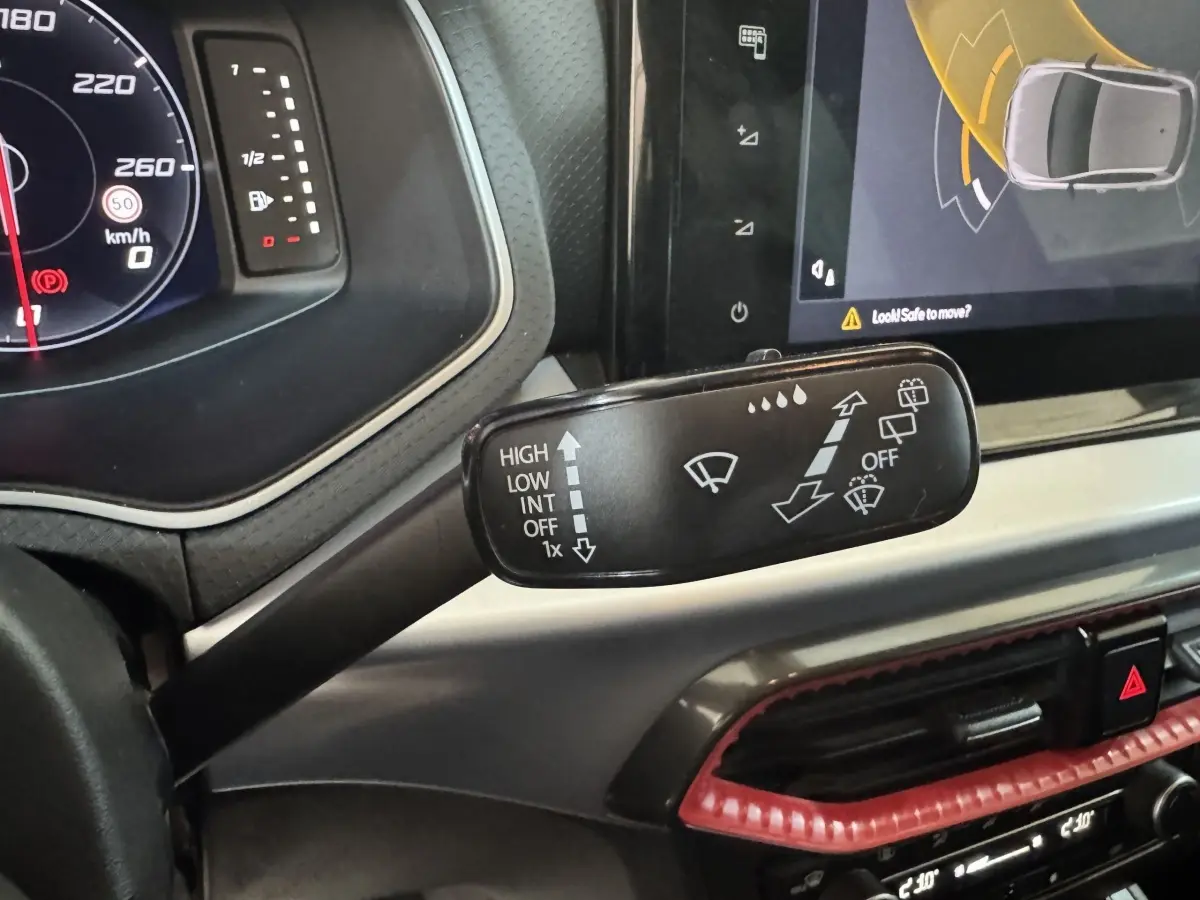 Gros plan sur la commande des essuie-glaces à gauche du volant dans l’habitacle rouge et noir d’une SEAT Ibiza 2024.