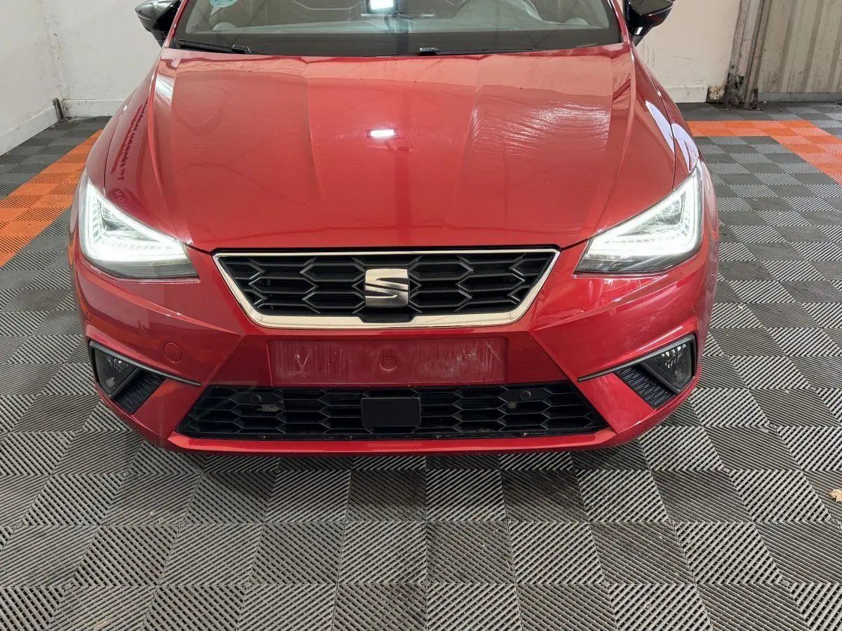 Vue de face d'une SEAT Ibiza rouge 2024 avec phares LED allumés et calandre hexagonale noire.