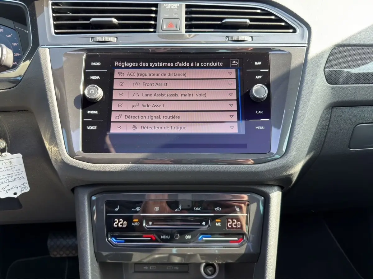 Vue rapprochée du tableau de bord noir du Volkswagen Tiguan 2022, avec écran tactile et commandes climatisation digitales.