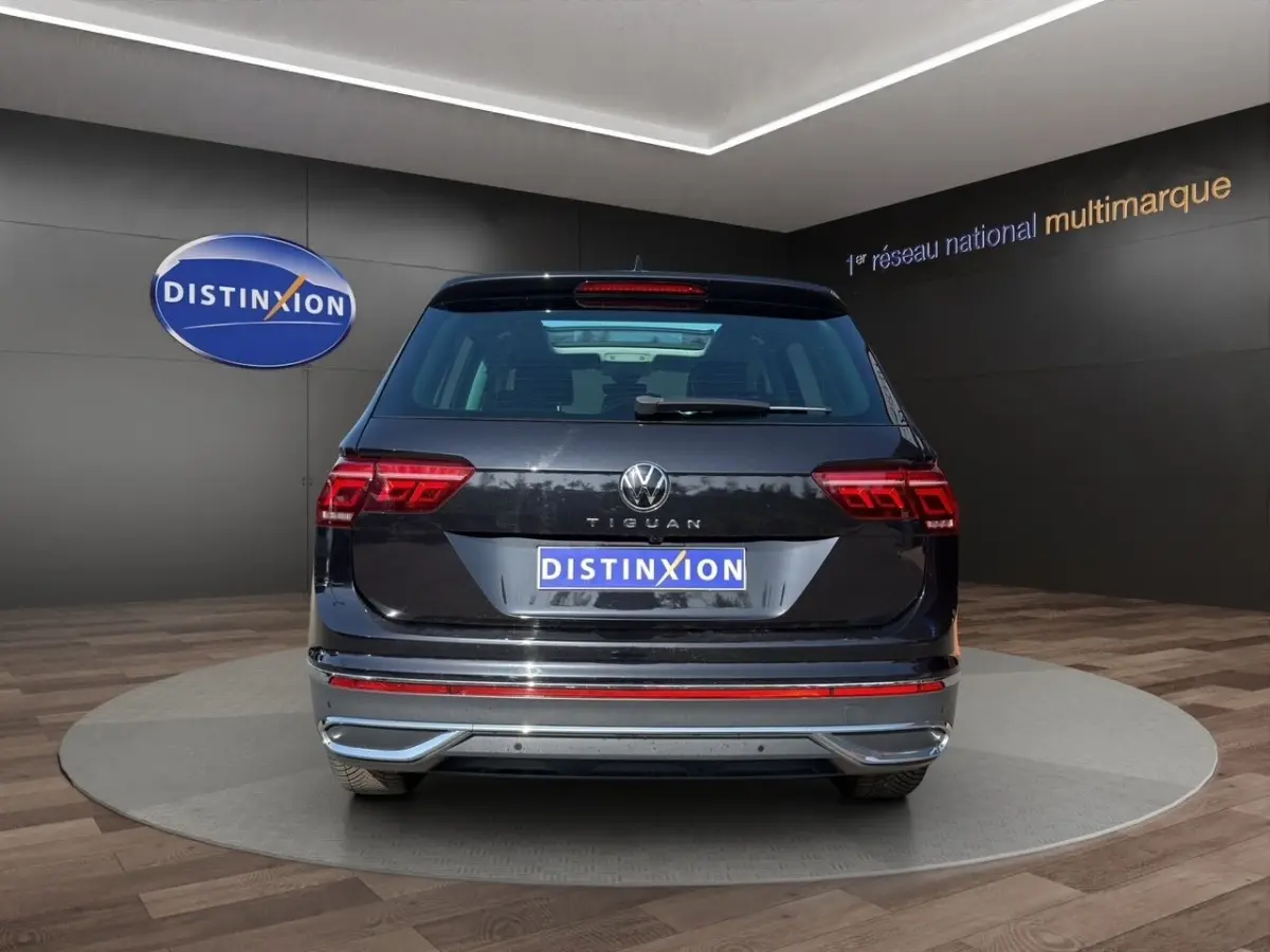 Vue arrière d'un Volkswagen Tiguan noir 2022 avec feux LED et logo distinctif sur fond de showroom.