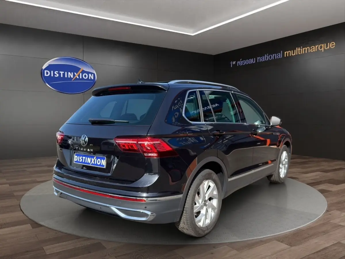 Volkswagen Tiguan noir vue 3/4 arrière droit en showroom avec jantes argentées et toit ouvrant.