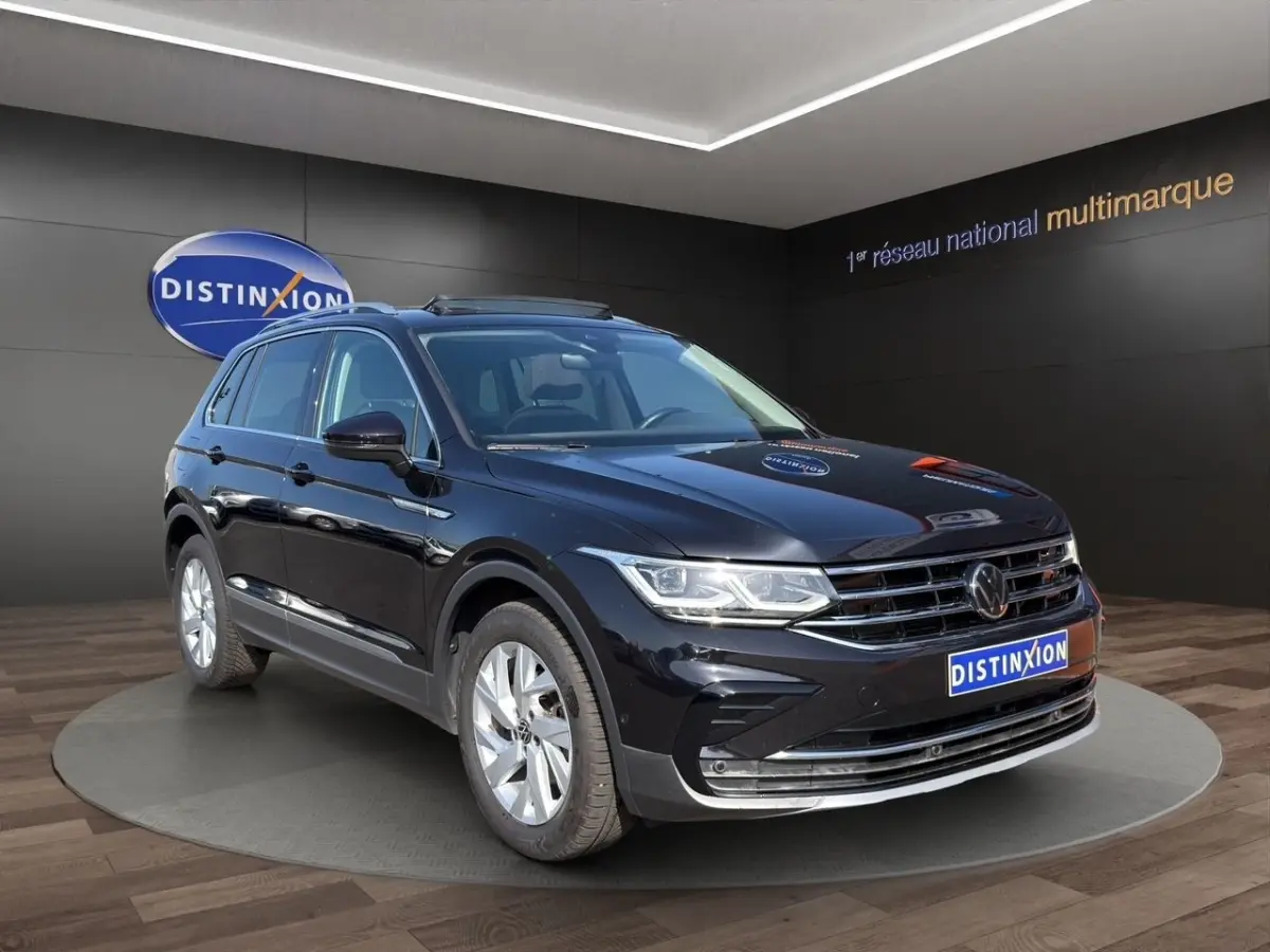 Volkswagen Tiguan noir en 3/4 avant droit, avec jantes argentées et toit ouvrant électrique visible.