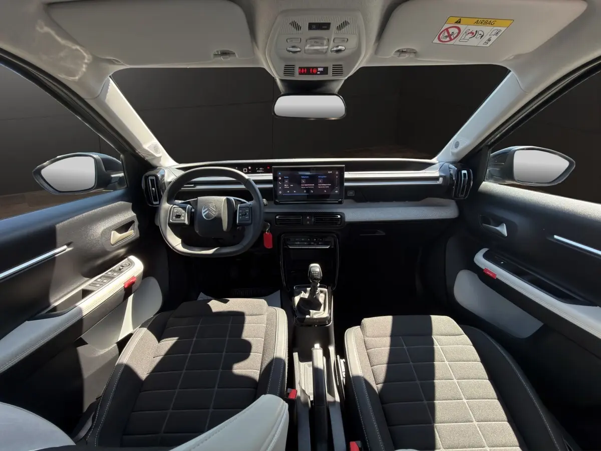 Vue intérieure avant de la Citroën C3 2025, tableau de bord avec écran tactile 10,25 pouces et volant cuir multifonctions.