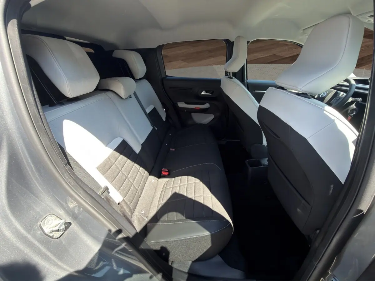 Vue intérieure arrière côté gauche de la Citroën C3 2025 gris foncé, sièges bi-ton noir et blanc avec appuie-têtes.