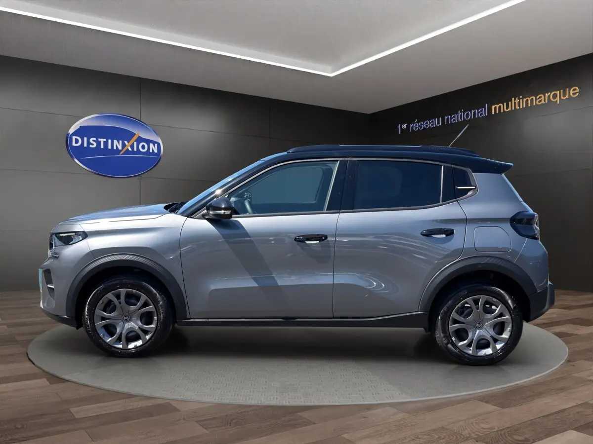Profil droit d'une Citroën C3 2025 gris foncé avec toit noir et jantes alliage en showroom.