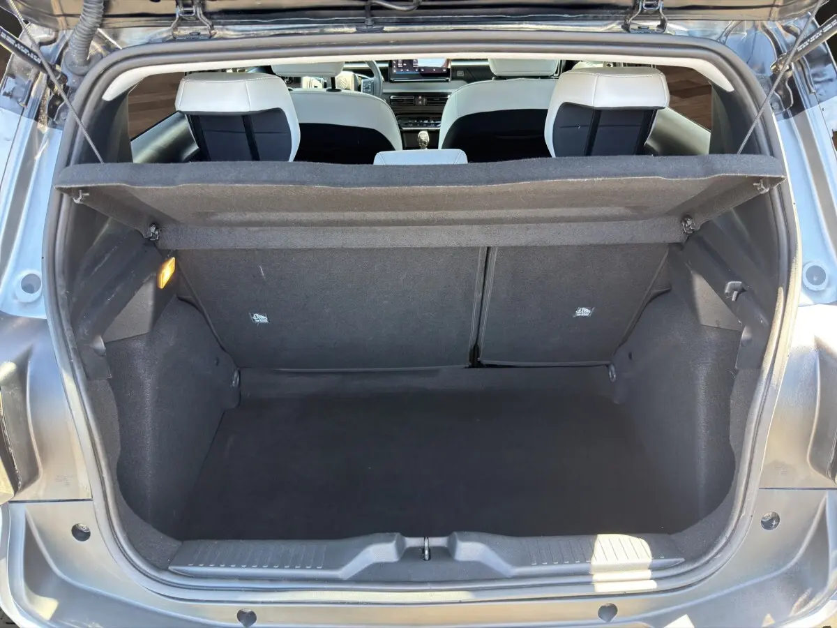 Coffre ouvert vu de l'arrière d'une Citroën C3 gris foncé, intérieur noir avec banquette arrière visible.