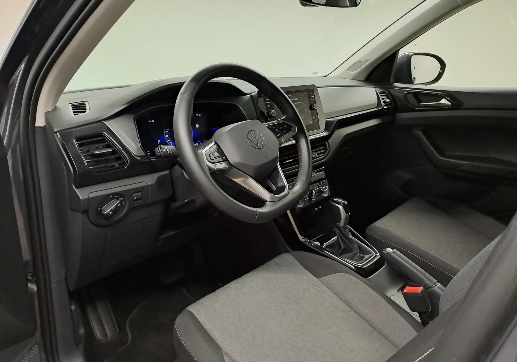 Vue intérieure côté conducteur du Volkswagen T-Cross 2025, tableau de bord moderne avec volant multifonction et sellerie grise.