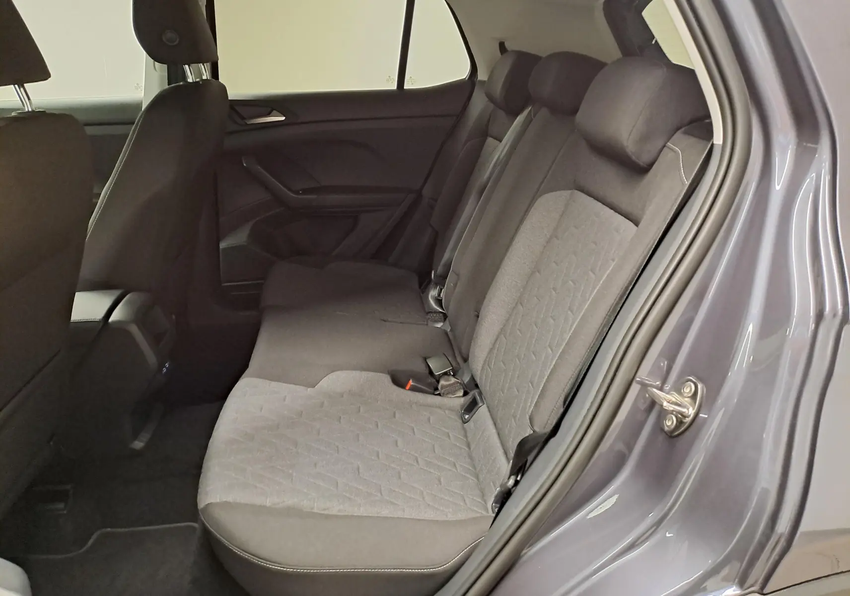 Vue intérieure côté droit des sièges arrière gris tissu du Volkswagen T-Cross 2025 en peinture métallisée Gris Cendré.