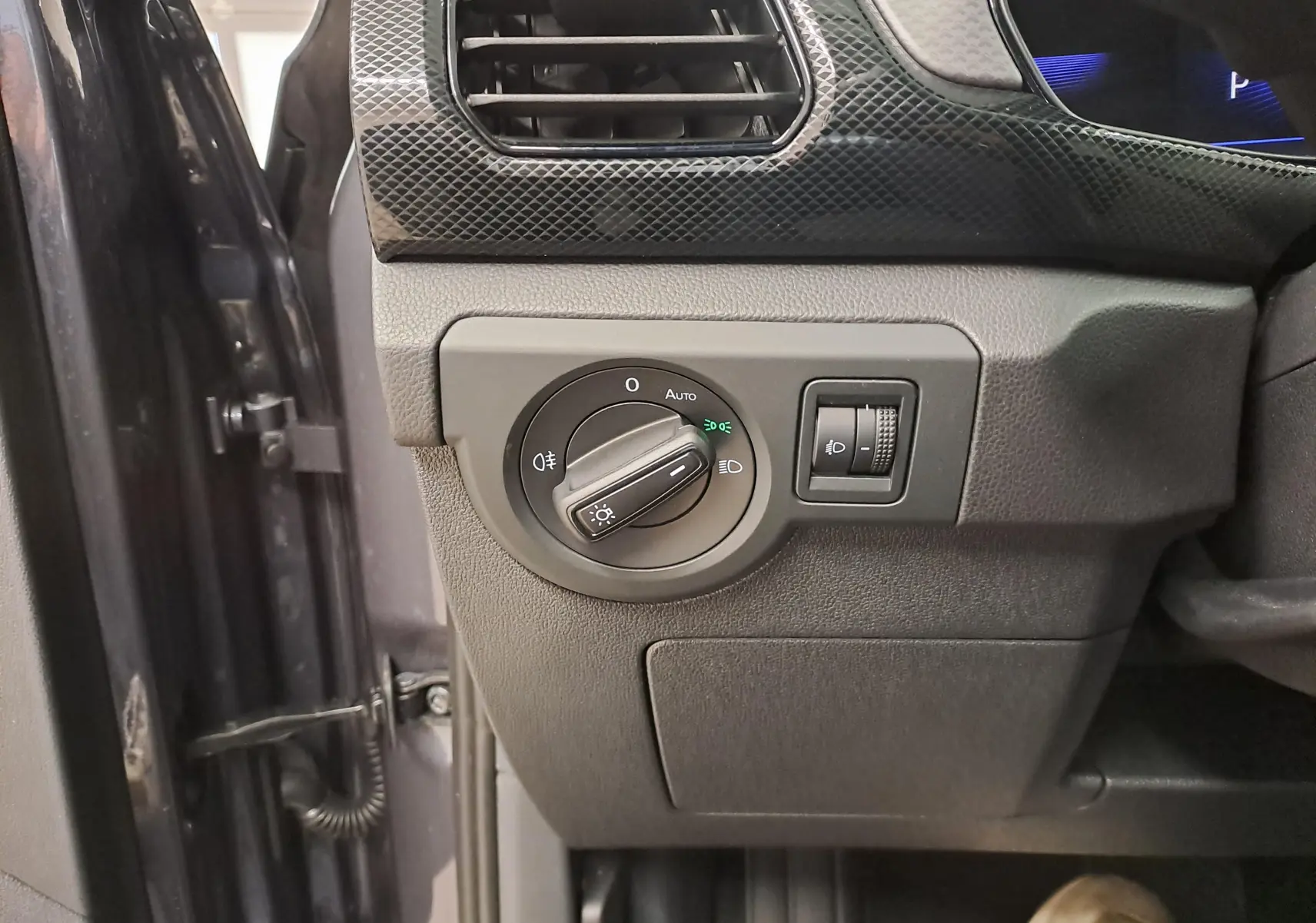 Détail du tableau de bord côté gauche du Volkswagen T-Cross 2025 gris cendré, avec commande des phares et réglage d’intensité.