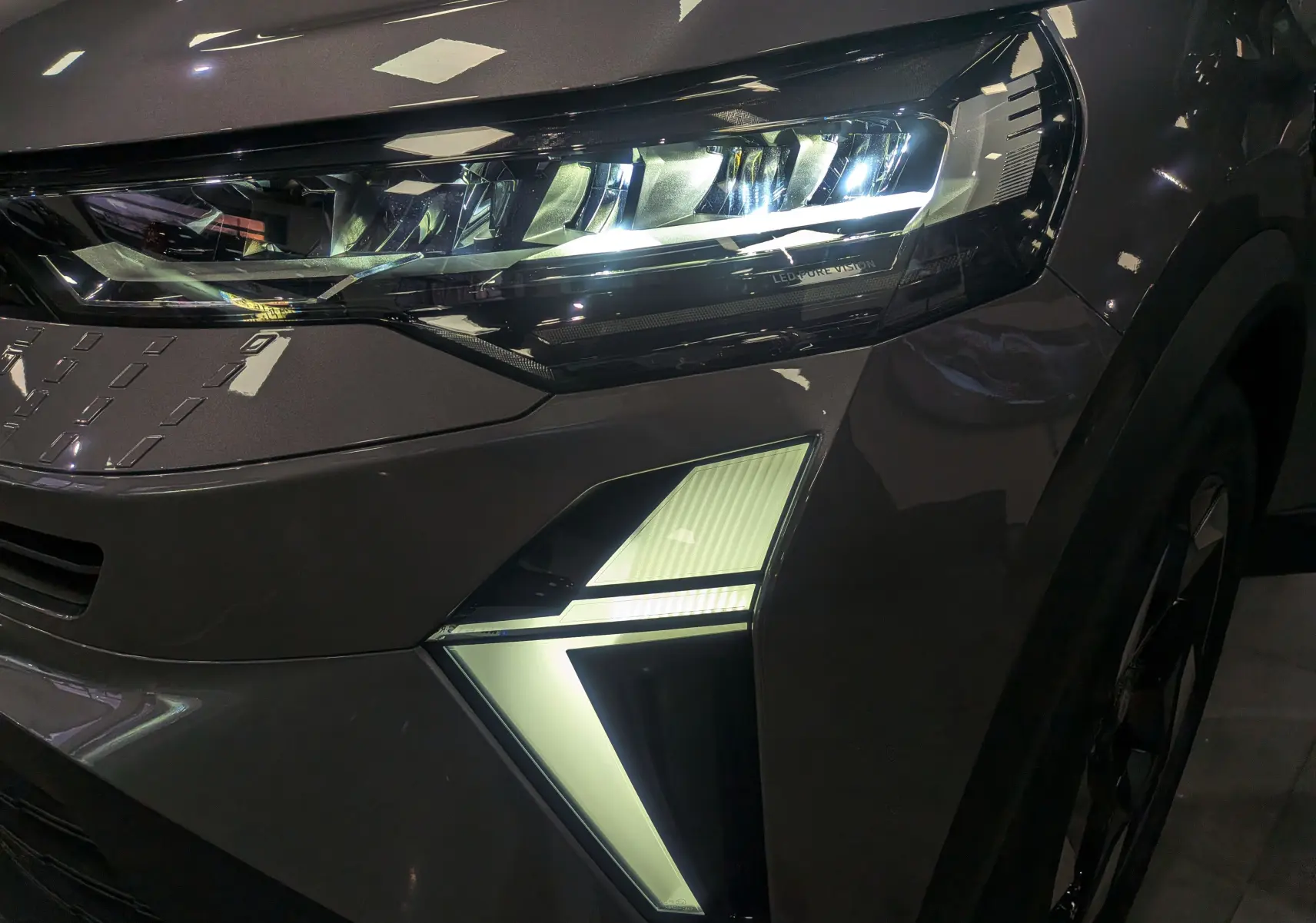 Gros plan sur le phare avant droit du Renault Captur Gris Cassiopé 2025 avec éclairage LED distinctif en forme de flèche.