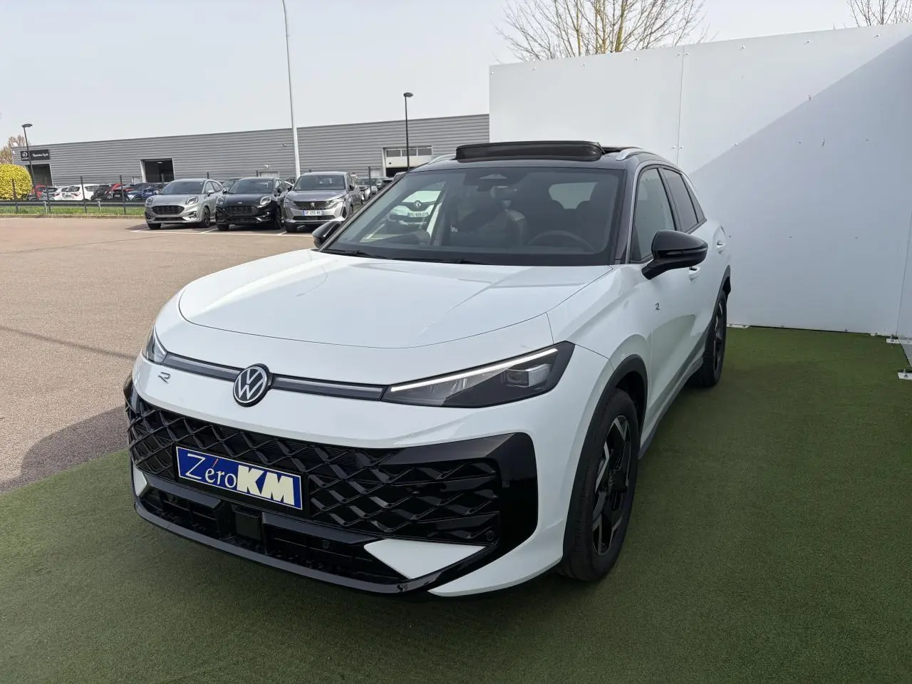 Volkswagen T-Roc blanc pur avec toit noir, vue 3/4 avant droite, calandre noire et jantes noires distinctives.