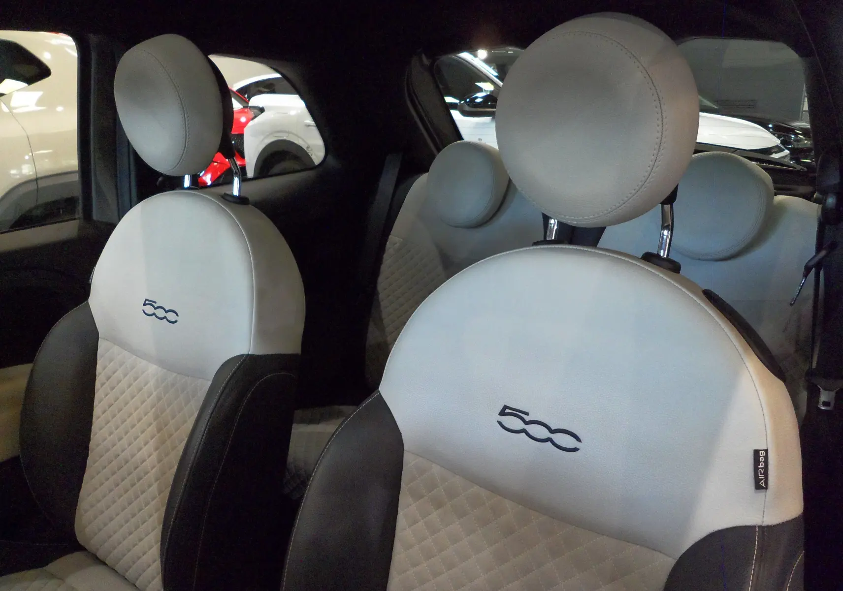 Vue rapprochée des sièges avant en cuir clair avec logo 500, intérieur du FIAT 500 Electroclash Grey 2021.