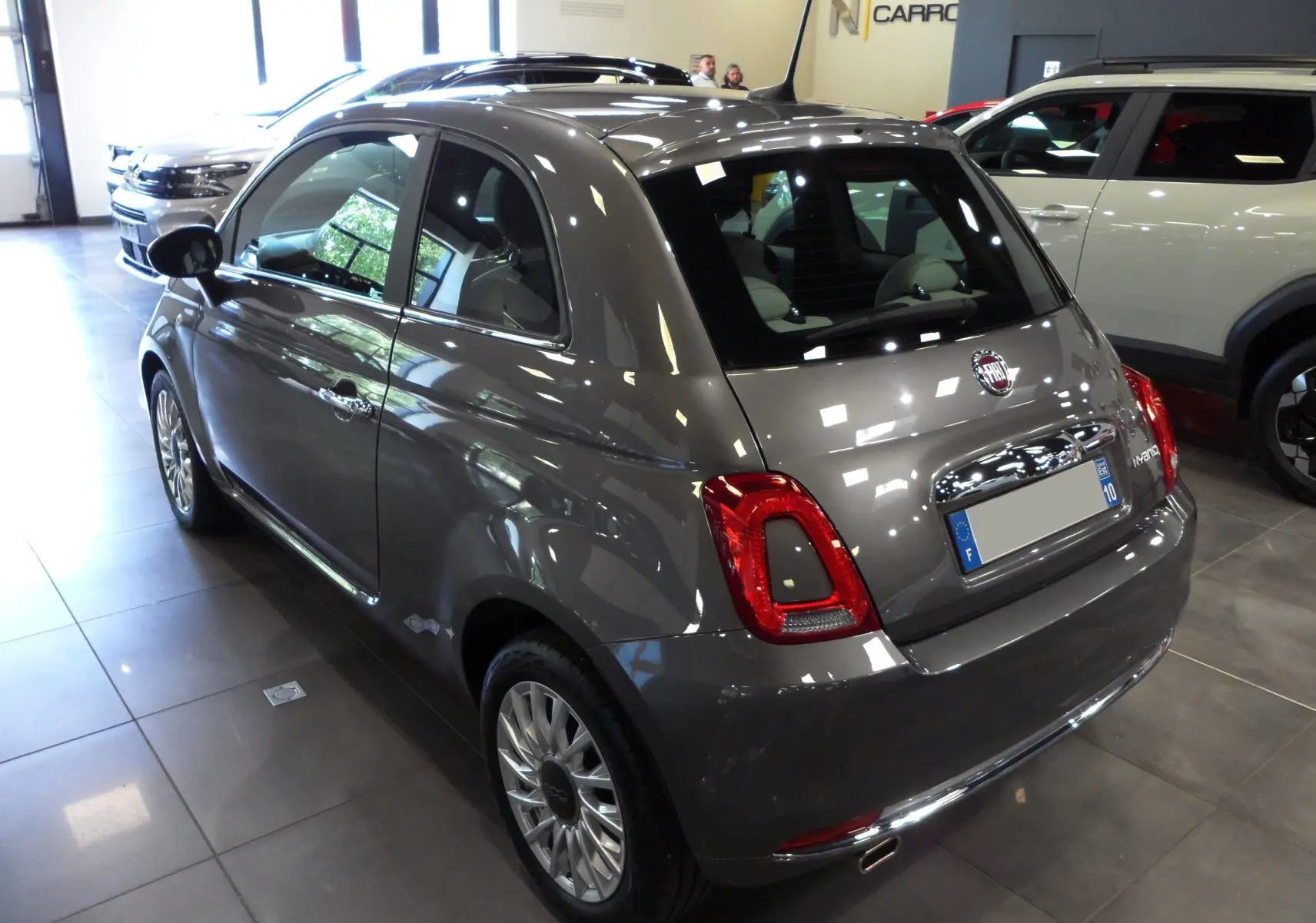 Fiat 500 Electroclash Grey vue 3/4 arrière droit en intérieur, avec feux arrière rouges et jantes alliage.