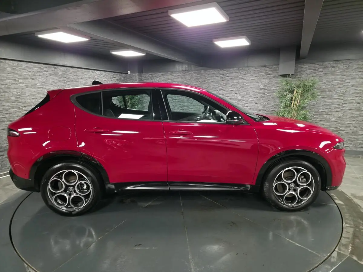 Vue de profil côté gauche d'un Alfa Romeo Tonale rouge avec jantes alliage 18 pouces et détails noirs brillants.