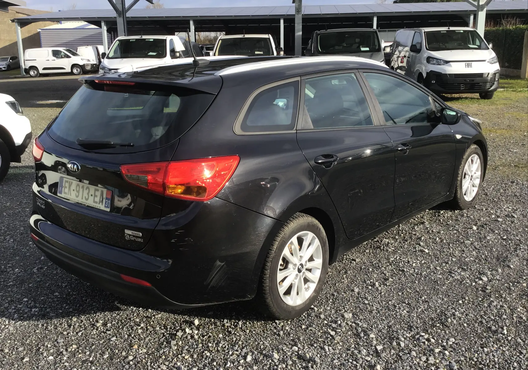 Vue 3/4 arrière droite d'une KIA CEE'D SW noire de 2017, avec feux arrière allumés et jantes alliage 16 pouces.