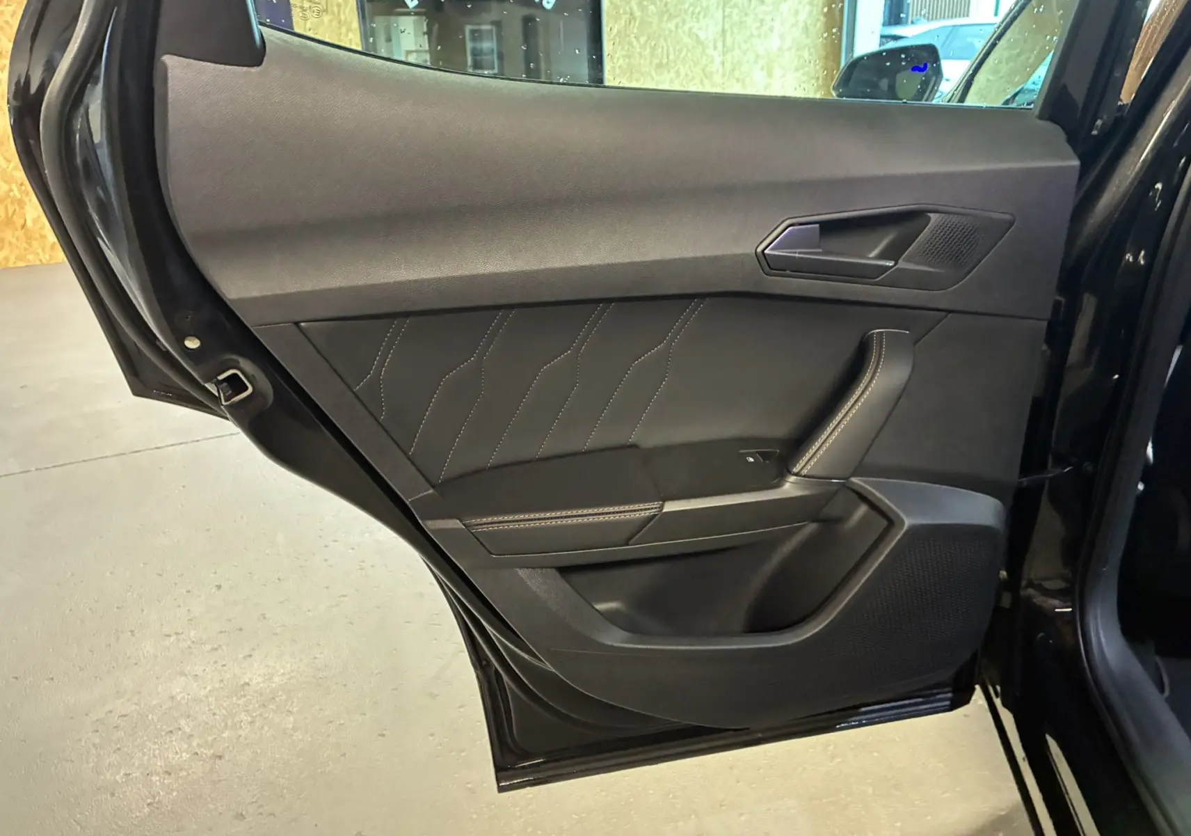 Vue rapprochée de la porte arrière gauche noire du CUPRA Formentor 1.4 E-HYBRID 2023 avec surpiqûres contrastées.