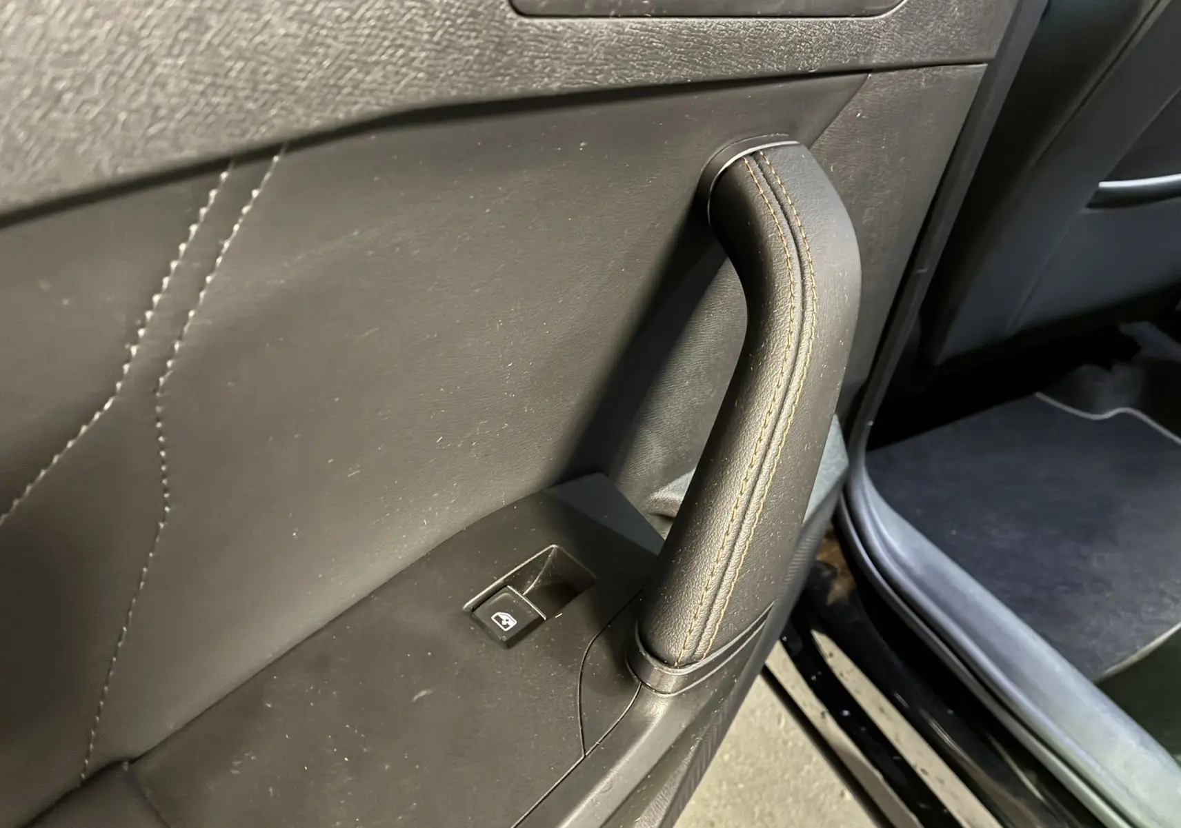 Poignée de porte intérieure en cuir noir avec surpiqûres marron sur la porte côté gauche d'une CUPRA Formentor 2023.